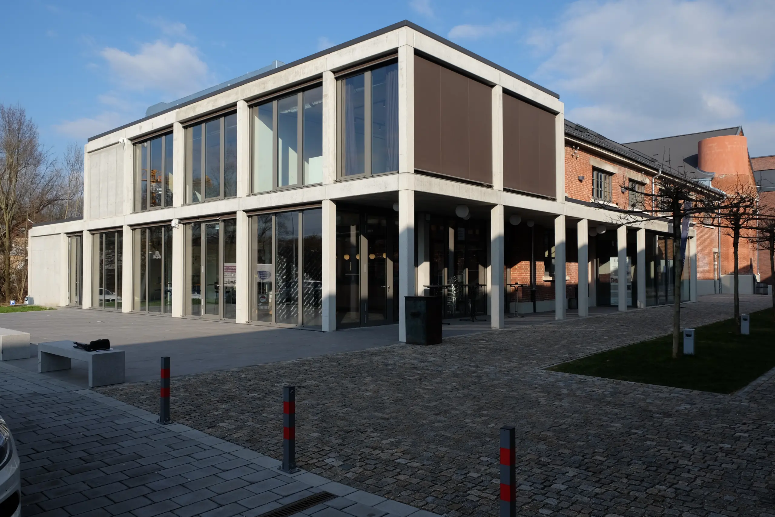 Öffentlicher Neubau in Sichtbeton-Skelettbauweise neben saniertem Backsteinbau